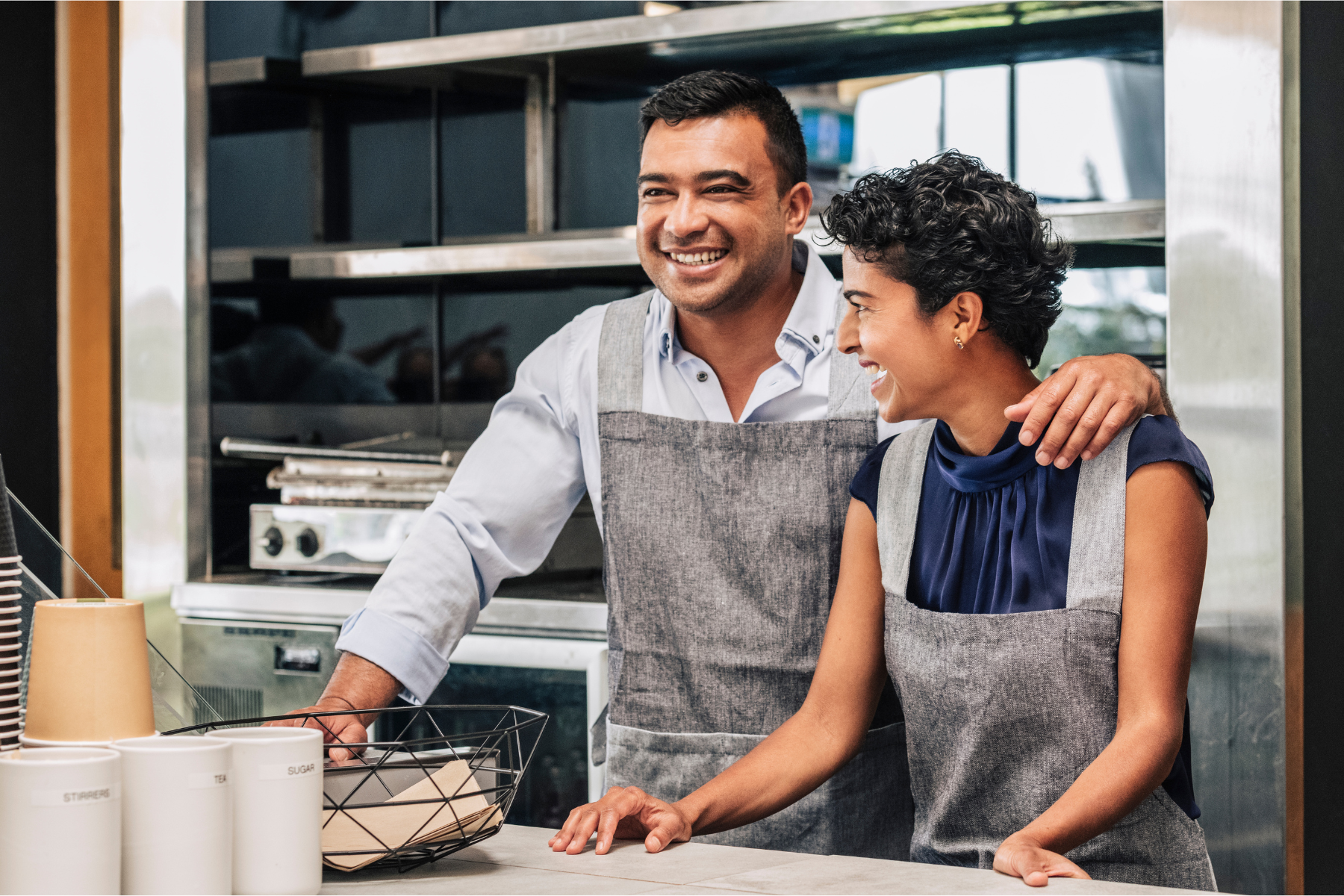 Small business owner stands with arm around employee