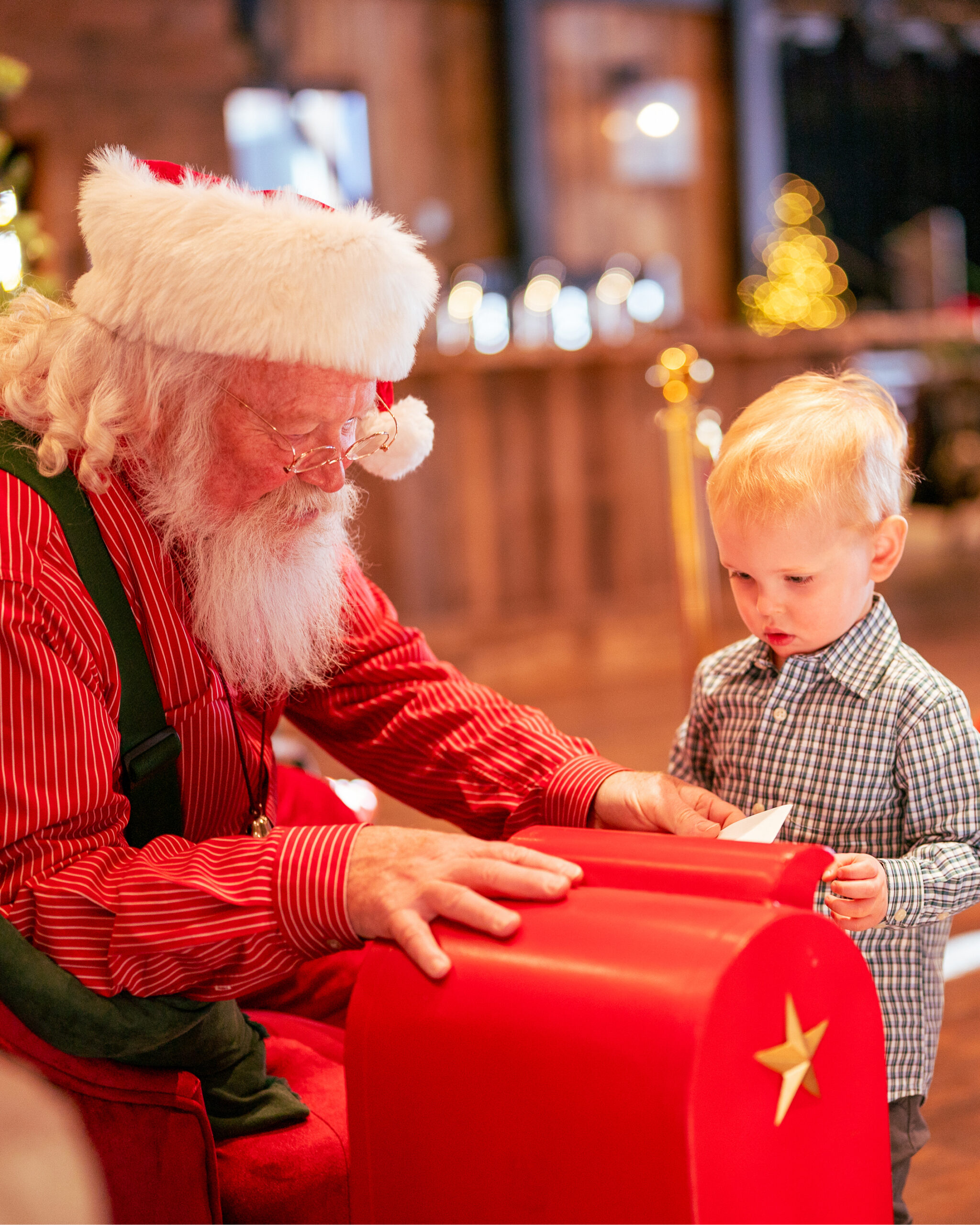 santa helping a young boy deliver a christmas letter 