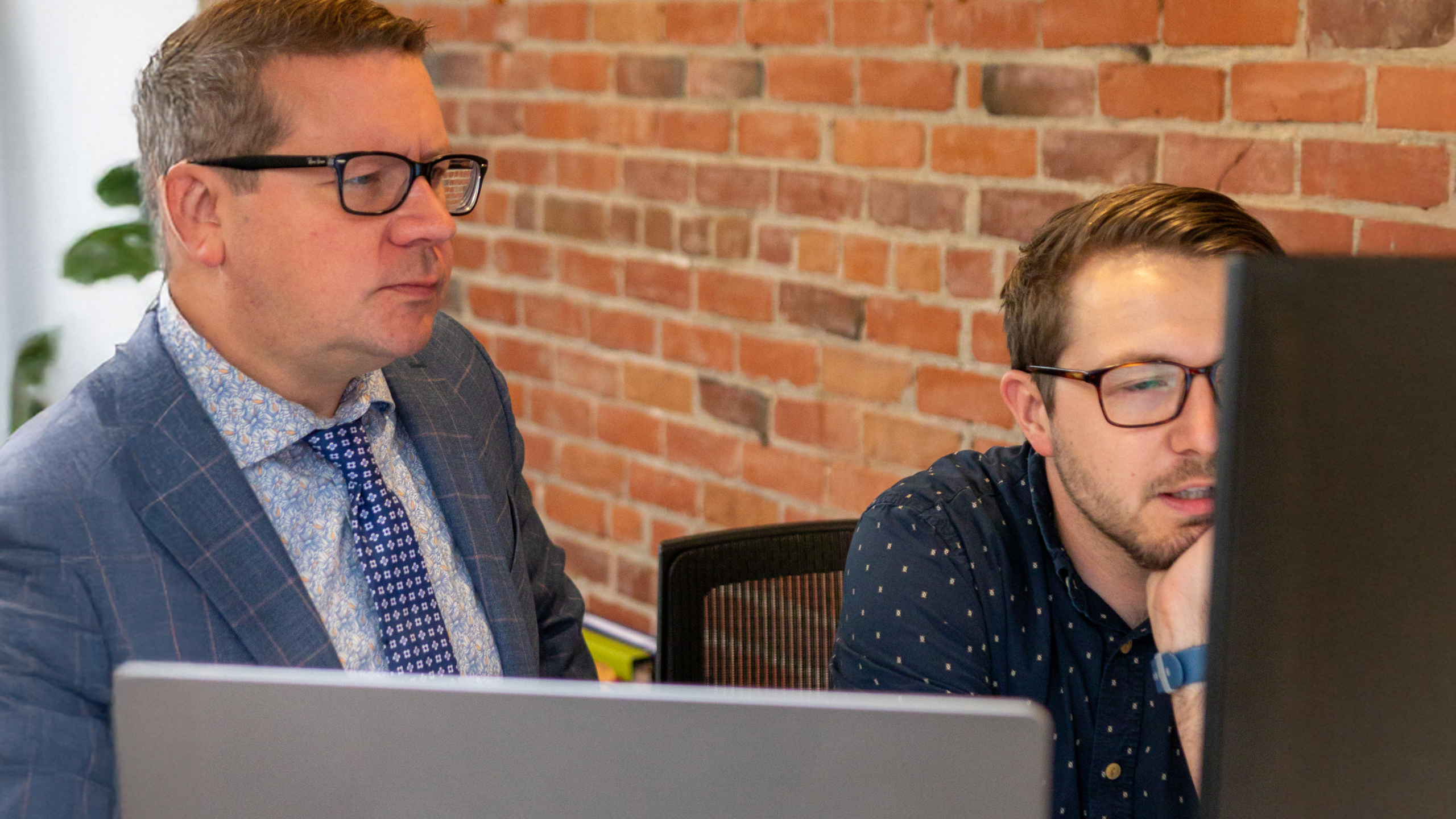 Two men prioritizing work on their computer.